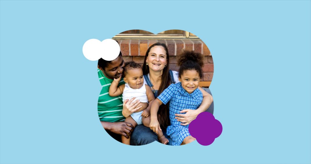 A smiling family with two parents and two young children sitting together outdoors, framed inside a playful cloud-shaped graphic on a light blue background with purple and white decorative shapes.