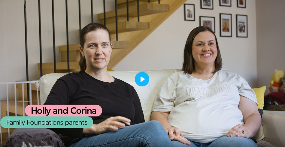 Two expectant parents sitting together on a couch during an interview about LGBTQIA+ family planning and parenting support.